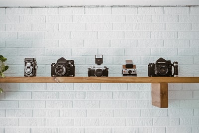 棕色木壁架上的黑白照相机
